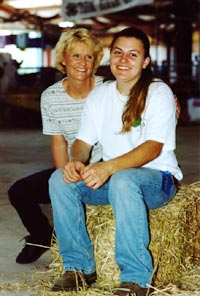 mother and daughter sit on haybale